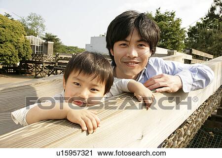 Stock Image - A small boy with his father rests on a netted bridge. Fotosearch
