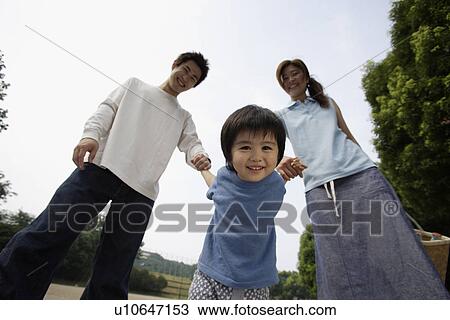 Stock Image - A young couple with a boy in park. Fotosearch