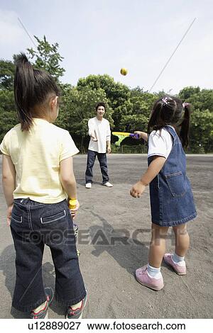Stock Photo - A young father playing catch with daughters. Fotosearch