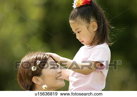 A young girl putting flowers in the hair of her mother View Large Photo Image Stock Photo - A young girl putting flowers in the hair of her mother. Fotosearch