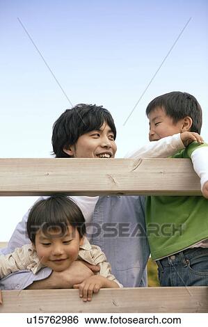 Stock Photograph - Father enjoys being with his two sons near the wooden planks. Fotosearch