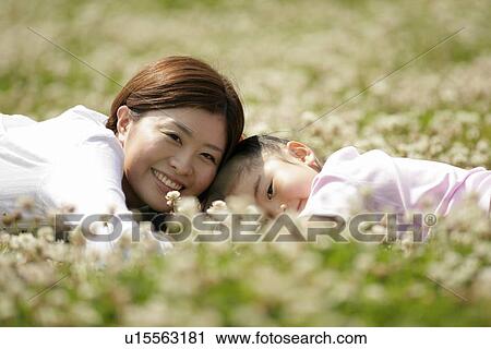 Stock Image - Mother and a daughter lying in a garden amidst flowers. Fotosearch