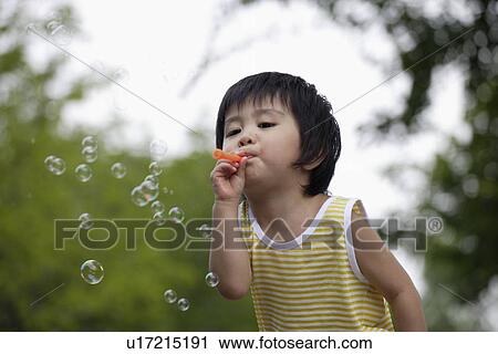 Stock Image - A boy blowing bubbles. Fotosearch