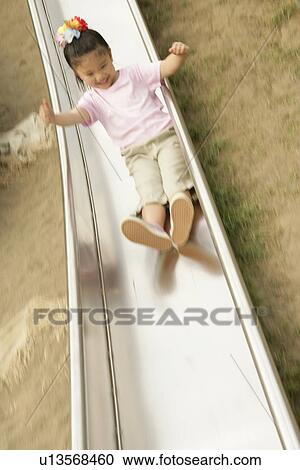 Stock Image - A girl enjoys herself sliding in the garden. Fotosearch