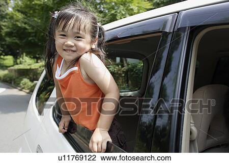 Stock Image - A girl leaning forward from a car window. Fotosearch