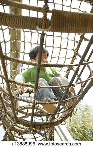 A small boy enjoying the movement in the netted cage View Large Photo Image Stock Photograph - A small boy enjoying the movement in the netted cage. Fotosearch