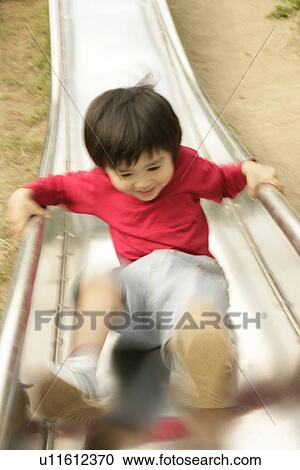 Stock Image - A small boy enjoys himself sliding in the garden. Fotosearch