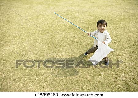 A small boy holding a net stands amidst the ground View Large Photo Image Stock Image - A small boy holding a net stands amidst the ground. Fotosearch