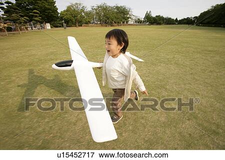 A small boy running on the ground as he holds an aeroplane in his hand View Large Photo Image Stock Photo - A small boy running on the ground as he holds an aeroplane in his hand. Fotosearch