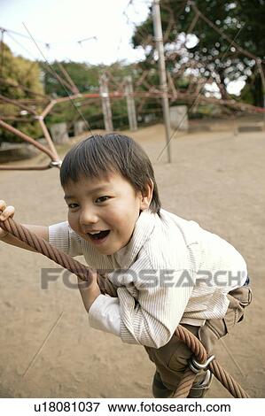 A young boy swinging on a rope in the park View Large Photo Image Stock Photo - A young boy swinging on a rope in the park. Fotosearch