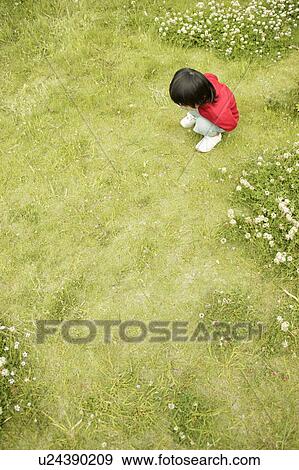 Stock Photo - Small boy staring at the grass in the garden. Fotosearch