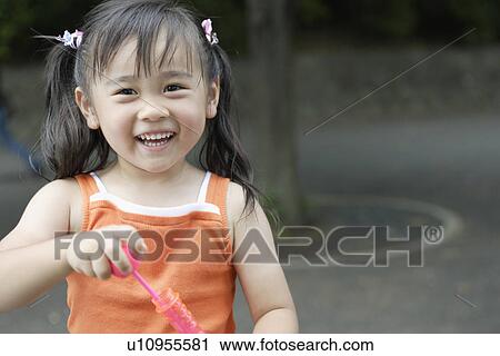 Stock Image - Smiling girl holding bubble gun. Fotosearch