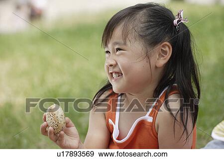 Smiling girl holds a bread View Large Photo Image Stock Photo - Smiling girl holds a bread. Fotosearch