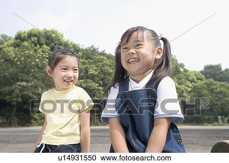 Stock Image - Two girls smiling in park. Fotosearch