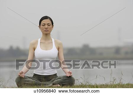 Stock Image - Front view of a woman in lotus position. Fotosearch