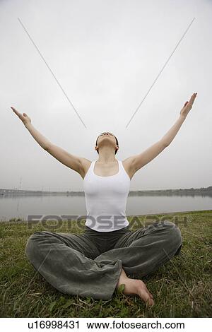 Stock Image - Front view of a young woman in lotus position. Fotosearch