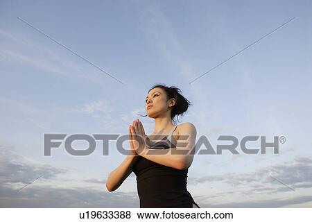 Low angle view of young woman performing yoga View Large Photo Image Stock Photo - Low angle view of young woman performing yoga. Fotosearch