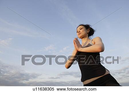 Low angle view of young woman performing yoga View Large Photo Image Stock Photography - Low angle view of young woman performing yoga. Fotosearch