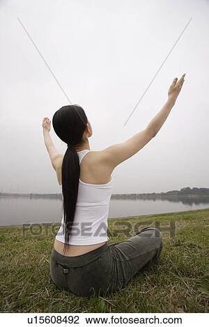 Stock Image - Rear view of a young woman in lotus position. Fotosearch