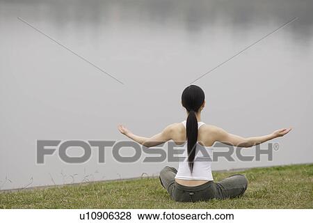 Stock Photo - Rear view of a young woman in lotus position. Fotosearch