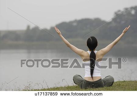 Stock Photo - Rear view of a young woman in lotus position. Fotosearch