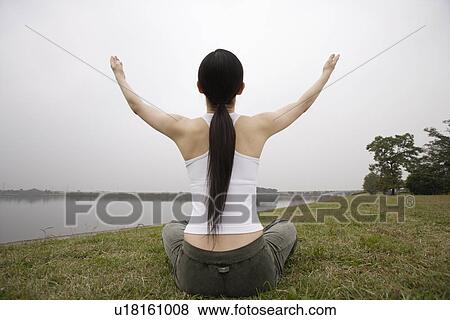 Stock Photo - Rear view of a young woman in lotus position. Fotosearch