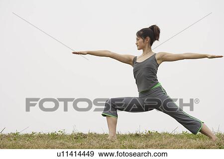Stock Photo - View of a young woman balancing on one leg. Fotosearch