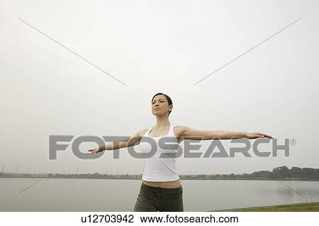 Stock Image - View of a young woman exercising outdoors. Fotosearch