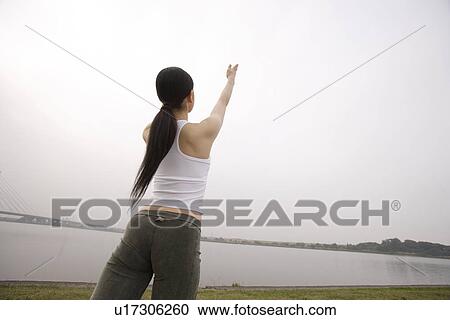 Stock Image - View of a young woman exercising outdoors. Fotosearch