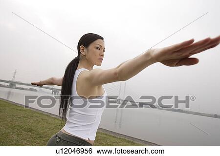 Stock Photograph - View of a young woman exercising outdoors. Fotosearch