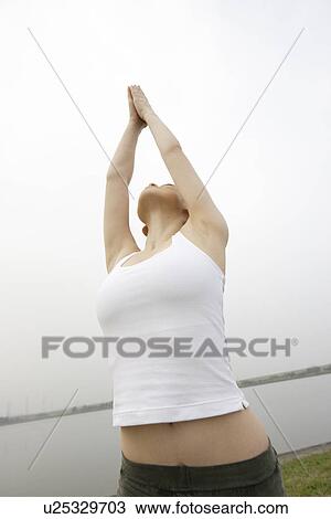 Stock Image - View of a young woman stretching out her hands towards the sky. Fotosearch