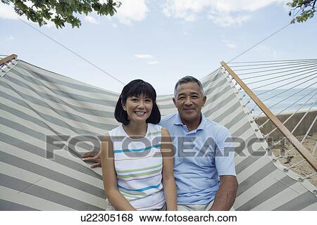 Stock Photo - A couple sitting on hammock. Fotosearch