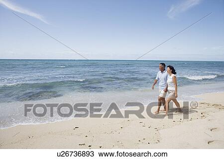 Stock Image - A couple walking at beach. Fotosearch