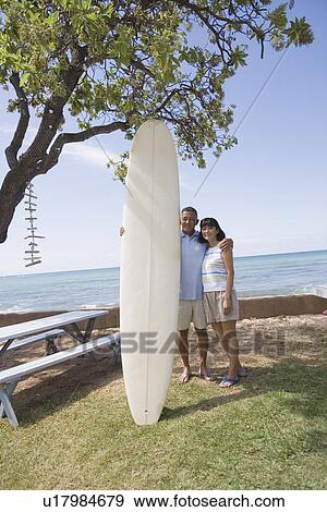 Stock Photo - A couple with surfboard smiling. Fotosearch