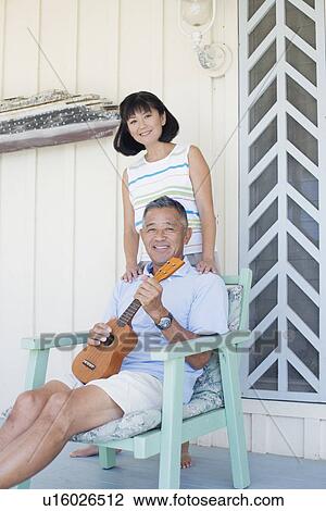 Man holding guitar and woman standing behind him View Large Photo Image Stock Image - Man holding guitar and woman standing behind him. Fotosearch
