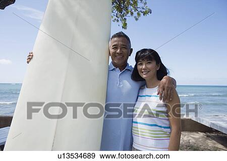 Stock Photo - Portrait of a couple with surfboard smiling. Fotosearch