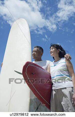 Stock Image - Profile of a couple with surfboards. Fotosearch