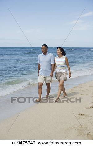 View of a couple walking at beach View Large Photo Image Stock Photo - View of a couple walking at beach. Fotosearch