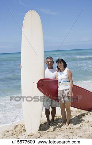 View of a couple with surfboards at beach View Large Photo Image Stock Photo - View of a couple with surfboards at beach. Fotosearch
