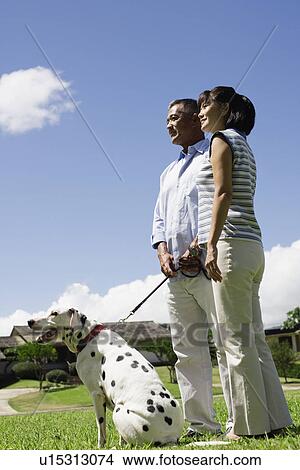 Picture - A couple standing in lawn with dog. Fotosearch