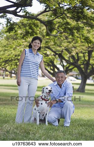 Stock Image - A couple with dog in park. Fotosearch