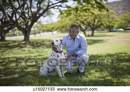 Man sitting with dog in park View Large Photo Image Stock Image - Man sitting with dog in park. Fotosearch