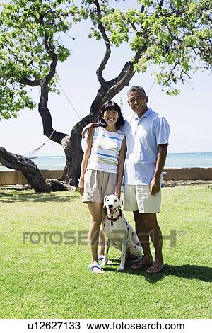 Stock Image - View of a couple standing with dog. Fotosearch