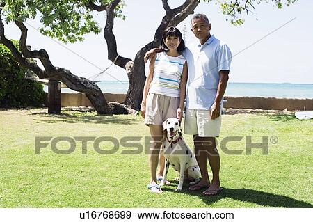 View of a couple standing with dog View Large Photo Image Stock Photo - View of a couple standing with dog. Fotosearch