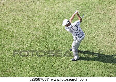 Stock Photo - Elevated view of a man hitting golf ball. Fotosearch