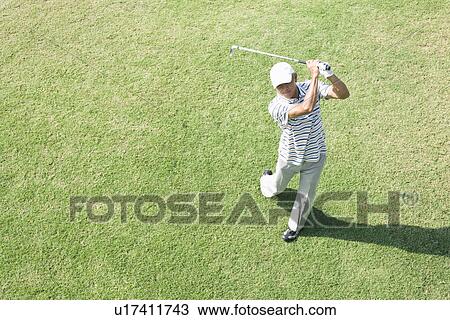 Stock Image - Elevated view of mature a man holding golf club. Fotosearch