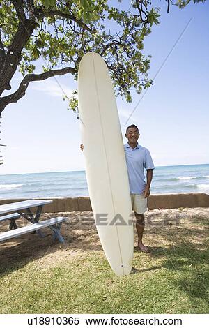 Stock Photography - Man standing with surfboard. Fotosearch