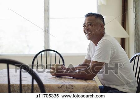 Stock Photography - Mature man holding cup laughing. Fotosearch