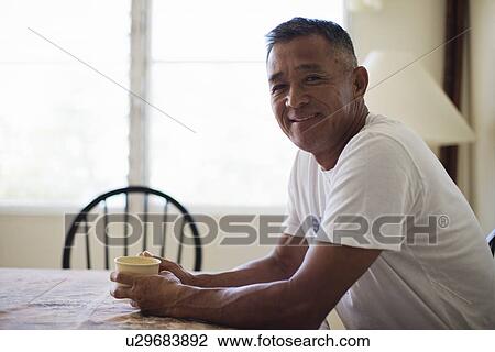 Stock Image - Mature man holding cup smiling. Fotosearch