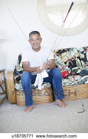 Stock Image - Mature man sitting on sofa. Fotosearch
